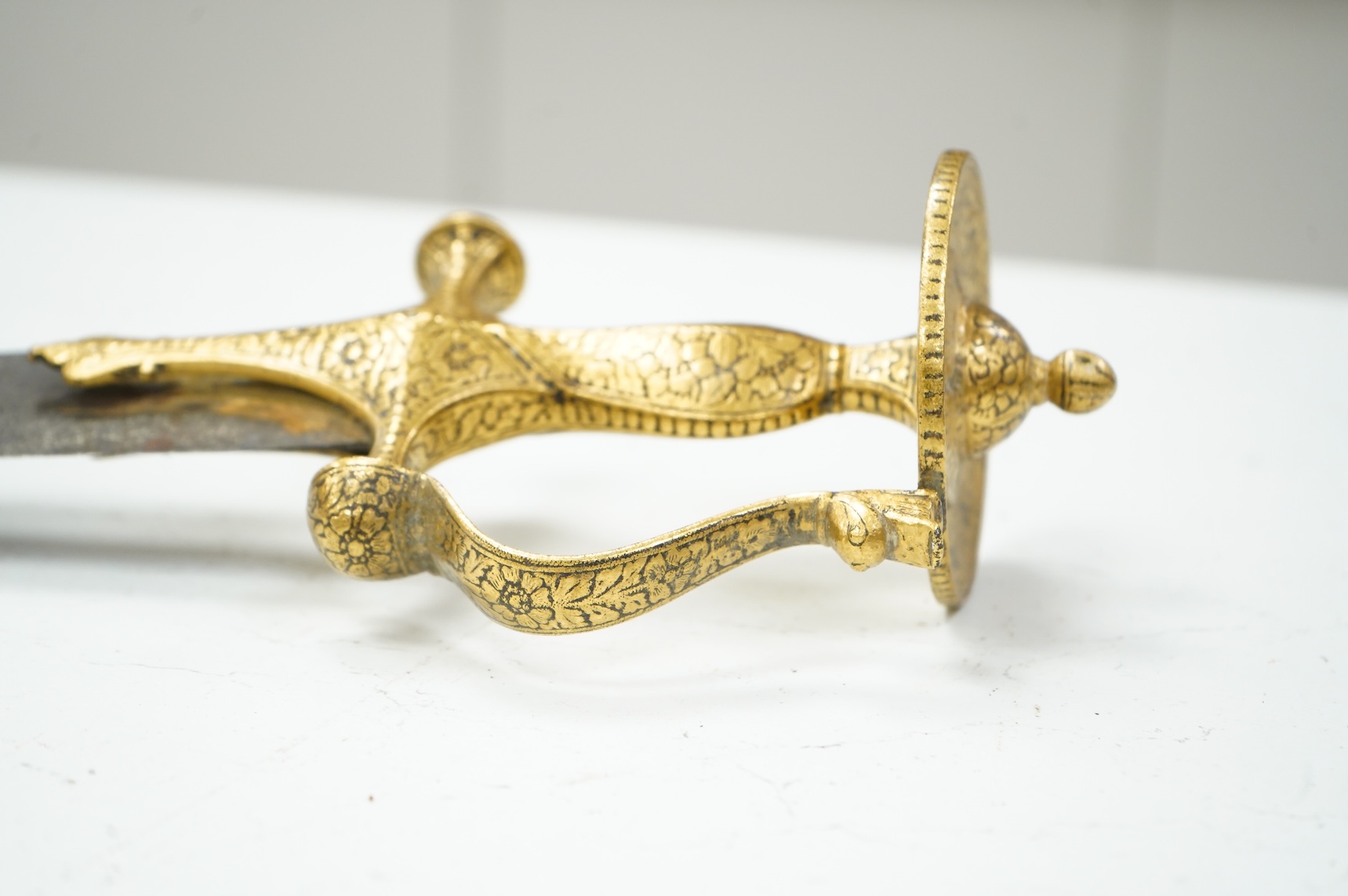 A good Indian sword tulwar, with 19th century broad curved single edge blade and iron hilt of conventional form entirely covered with flowering foliage